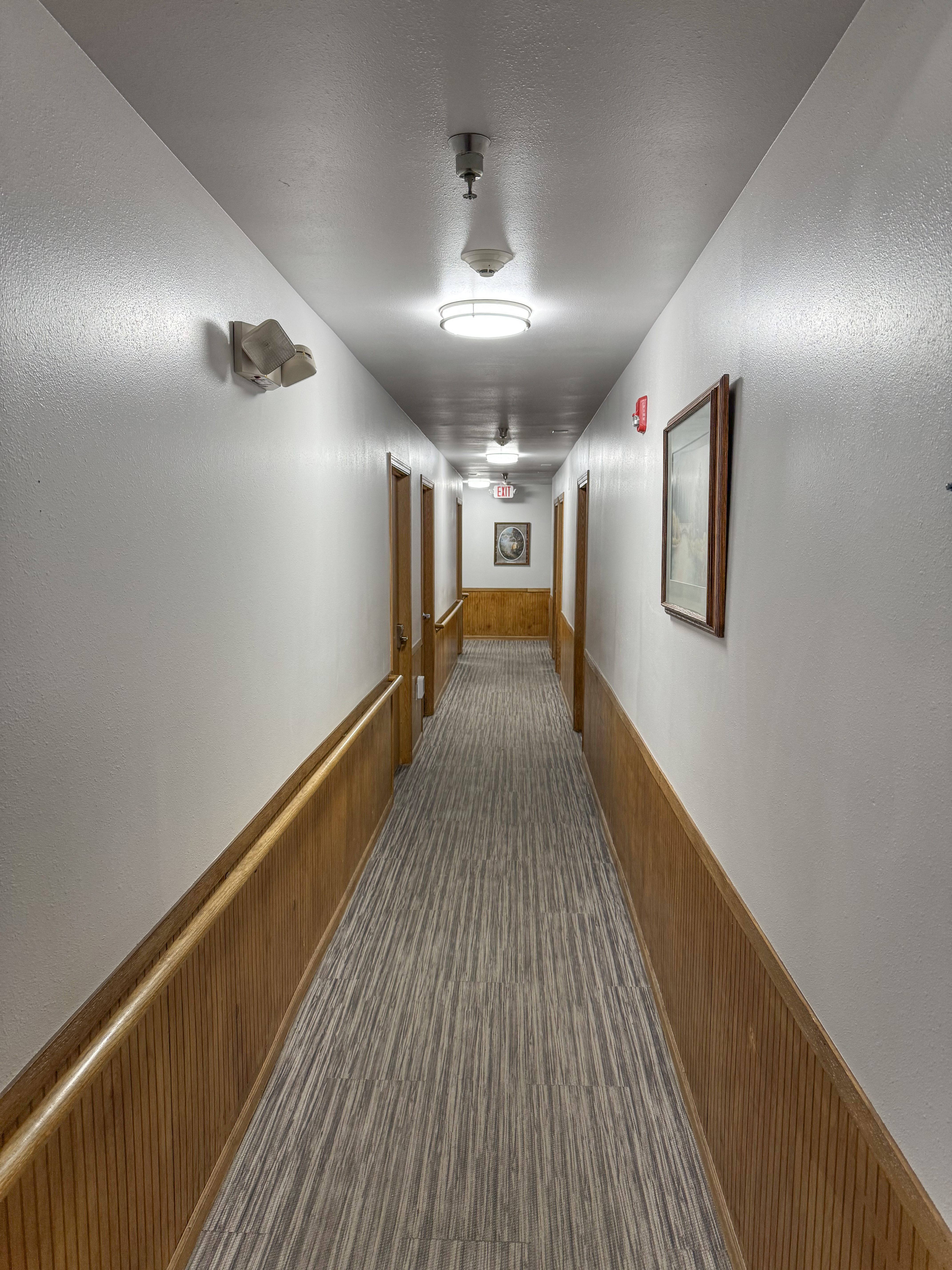 A long hallway with a carpeted floor and wooden trim.